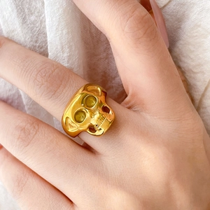 Vue détaillée d'une bague tête de mort punk plaquée or 18 carats portée au doigt