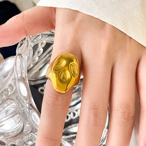 Détail macro d'une grosse bague dorée à texture lave et finition métallique irrégulière