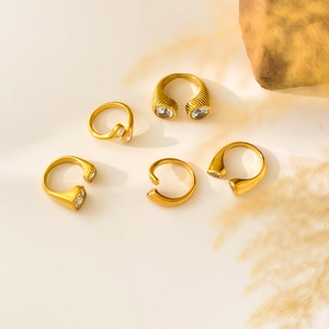 Flat lay of five 18K gold plated titanium snake rings with zircon stones and dry flowers