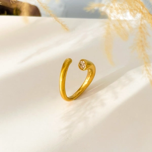 Detail of 18K gold snake ring with zircon stone, featuring soft floral shadows