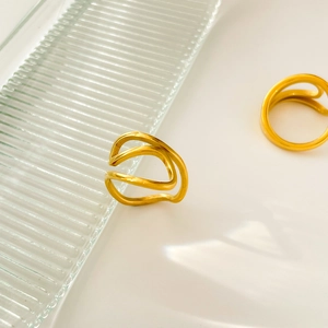 Detail showing wavy multi-layer 18K gold plated stackable ring on a glass surface