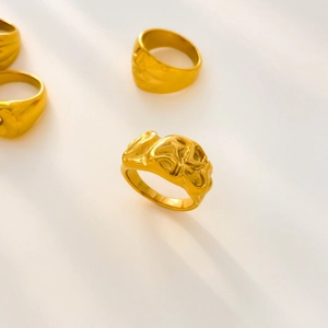 Dettaglio di anelli in acciaio al titanio placcato oro 18K con texture lavica irregolare