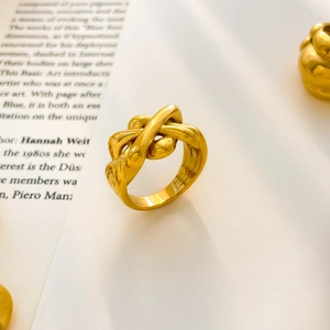 Primo piano di un anello placcato oro a tre strati su uno sfondo di un libro d'arte