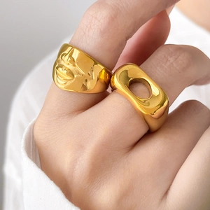 Dettaglio dell'anello con viso a rilievo e anello geometrico in oro 18 carati