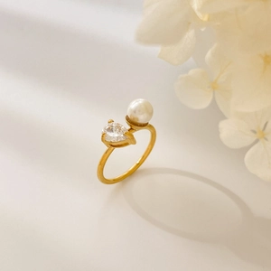Detailed shot of golden pear-cut zircon and white pearl on a curved double-layer ring
