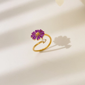 Detail of a golden open ring featuring a purple daisy flower and a sparkling zircon stone