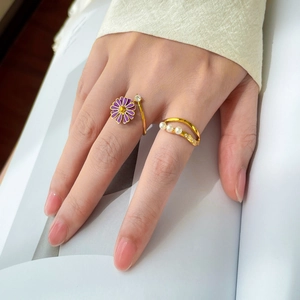 Detail of layered gold ring with pearls and purple enamel daisy on model hand