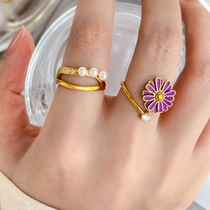 Macro shot of double-layer gold rings with purple daisy enamel and elegant pearls