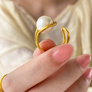 Macro view of gold teardrop ring with pearl on sleek curved double-layered lines