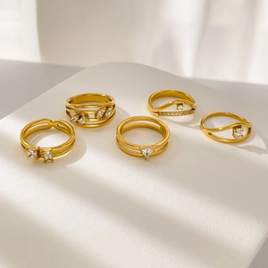 Ensemble de cinq bagues en acier titane plaqué or avec zircons géométriques