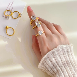 Détail de 6 bagues dorées ornées de zircons carrés et rectangulaires portées par un mannequin