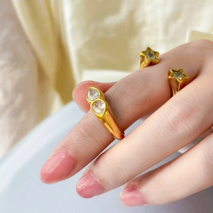 Detail shot of 18K gold plated rings set with star and teardrop zircon on silk background
