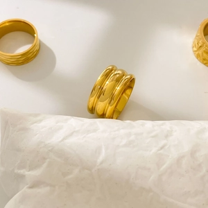 Macro detail of three 18K gold plated titanium steel rings with geometric textures