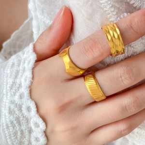 Close-up of three 18K gold-plated titanium rings with hammered, wavy, and diagonal textures