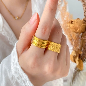 Detail of 18K gold plated titanium steel rings with textured patterns and triple arc grooves