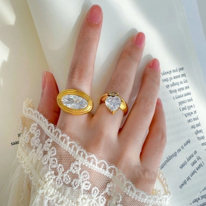 Detail of 18K gold plated rings with large oval and heart zircon stones on a female hand