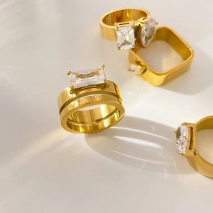 Detailed view of layered 18K gold plated rings with square and teardrop zircon accents