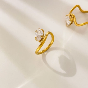 Macro shot of 18K gold plated ring with marquise-cut zircon on marble background