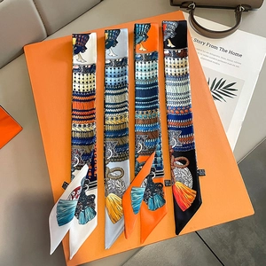 Close-up of four colorful patterned silk twilly scarves displayed on a luxury orange gift box