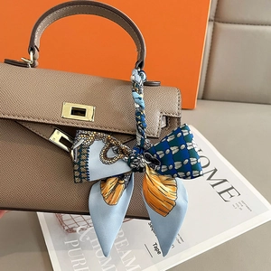 Taupe pebbled leather handbag with blue printed silk scarf tied on top handle