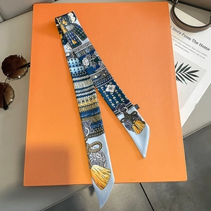 Close-up of silk twilly scarf with blue armor print on an orange gift box