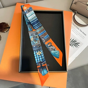 Detail shot of a silk twilly scarf with royal patterns on a luxury gift box