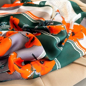 Close-up of silk-textured floral scarf with emerald green and bright orange patterns