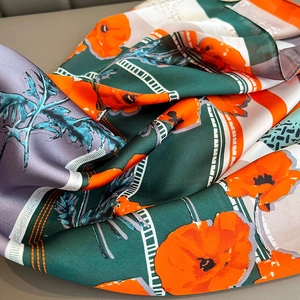 Detailed macro view of the silky fabric texture and orange floral print on a folded scarf