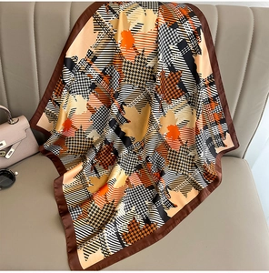 Detail of silk-texture square scarf featuring orange maple leaf and houndstooth pattern