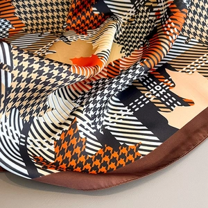 Detail of houndstooth silk scarf with autumn leaf patterns and rolled edge stitching