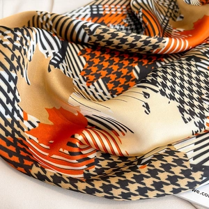 Detailed view of houndstooth and maple leaf pattern on silky satin square scarf