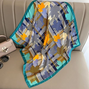 Detail of silk square scarf featuring houndstooth and maple leaf patterns on a beige sofa
