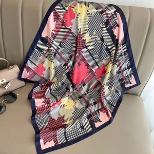 Close-up of houndstooth silk scarf with autumn leaf patterns draped on a leather sofa