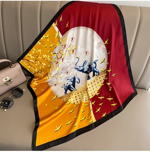 Detail of silk square scarf with oriental bird and elephant prints on a leather sofa