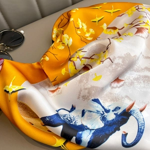 Detail of silk scarf showing blue elephant and yellow crane prints with ginkgo leaves