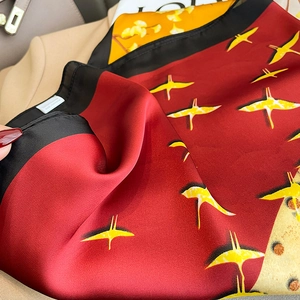 Detail of red silk scarf with yellow crane and ginkgo leaf prints with satin finish