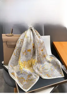 Silk square scarf with botanical print draped over a premium leather handbag detail