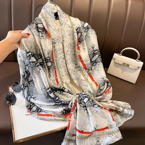 Fashion silk scarf with snakeskin print and gold chain pattern on leather background