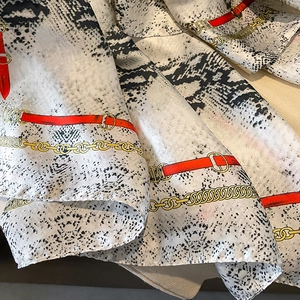 Silk-like scarf with snakeskin print, red belts and golden chain patterns on smooth fabric