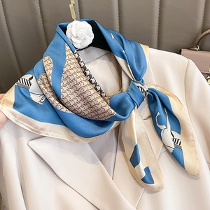 Elegant silk scarf with horse print and houndstooth pattern draped over a blazer