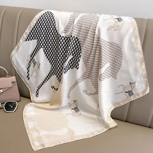 Silk square scarf featuring vintage horse silhouette and houndstooth patterns on a sofa