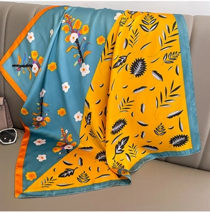 Détail d'un foulard en soie à motifs floraux drapé sur un canapé en cuir gris