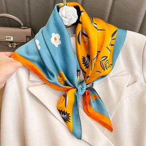 Carré de soie à imprimé floral bleu et orange noué sur un blazer blanc élégant
