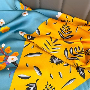 Carré de soie floral bleu et jaune avec fini satiné sur fond de cuir gris élégant