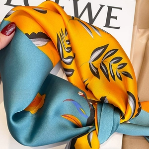 Gros plan d'un foulard en soie aux motifs de feuilles bleues et jaunes élégantes