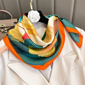 Carré de soie floral porté sur un col de costume beige avec des tons chauds et motifs
