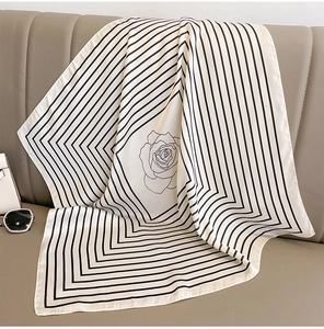 Detail of silk scarf with rose pattern draped on a leather sofa with fashion accessories