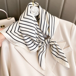 Elegant black and white striped silk scarf styled on a beige blazer for a modern look
