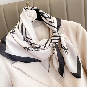 Foulard in seta minimalista bianco e nero annodato sul risvolto di un blazer