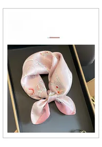 Détail d'un carré de soie rose avec imprimé classique de chaînes et boucles blanches
